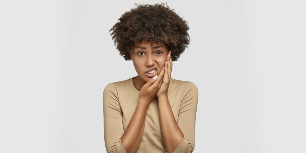 Mulher com dor nos dentes causada pelo bruxismo